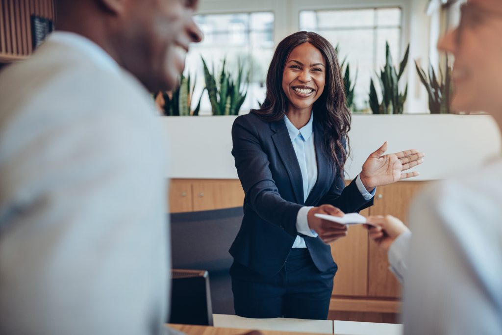 Laughing young African American hotel concierge helping guests check in