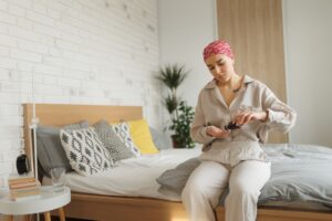 Young adult woman with cancer taking pills, cancer awareness concept.