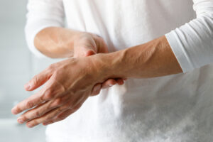 closeup of man holding hands that are painful caused by arthritis
